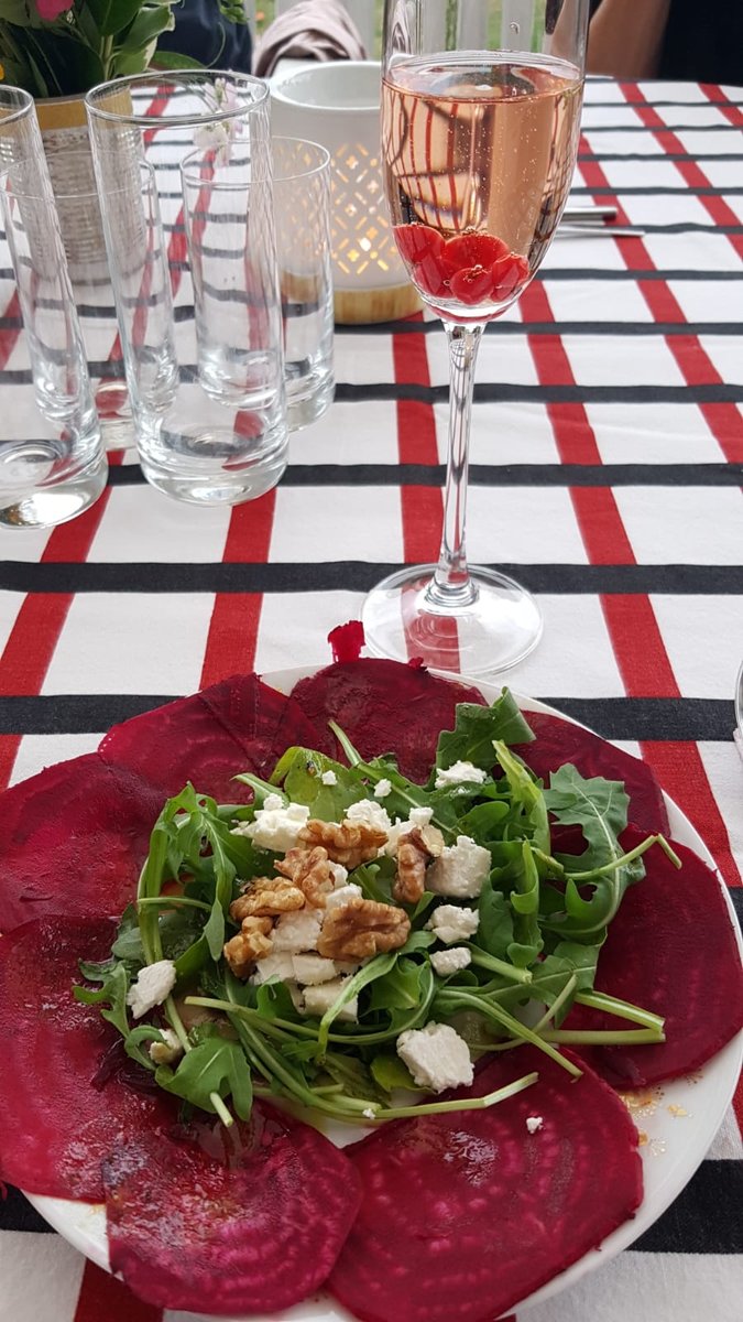 Rote-Bete-Carpaccio mit Rucola, Feta und Walnüssen auf einem Teller, dazu ein Glas Rosé