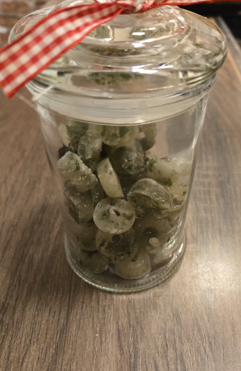 Fertige Kräuter-Hustenbonbons in einem Glas mit roter Schleife